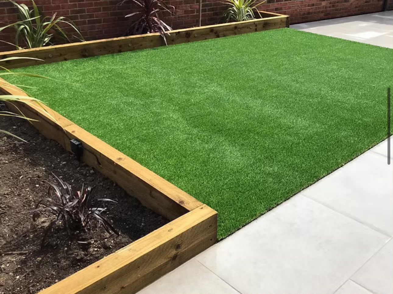 Finished rear garden with an artificial lawn, timber sleeper edging and a porcelain paving path.