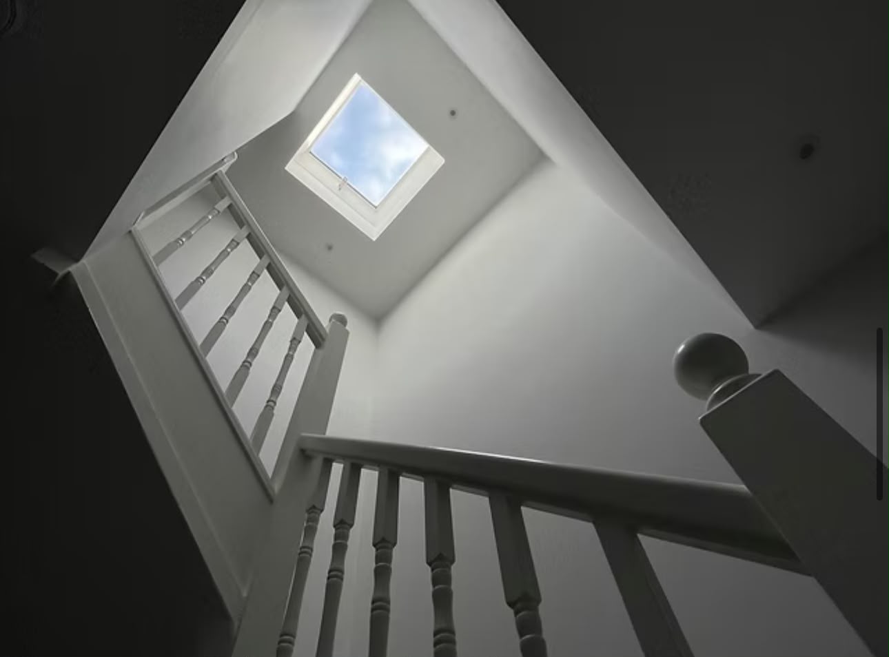 New staircase and painted balustrade rising into a loft conversion lit by a rooflight.